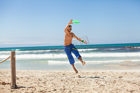 夏天在海滩上玩飞盘的迷人男人