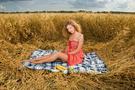 美丽的斯拉夫女孩在麦田野餐用苹果和香蕉