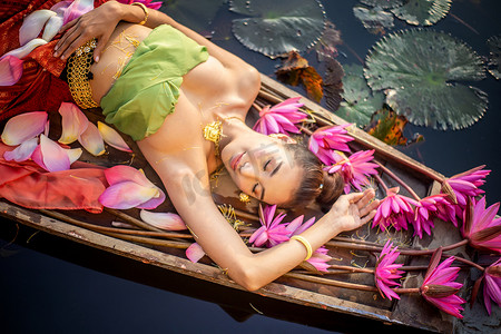 船上穿着传统服饰的年轻亚洲女性，池塘里的粉红色莲花。穿着传统服装的漂亮女孩。穿着复古泰式服饰的泰国女孩，穿着传统服饰的泰国女孩