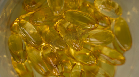 鱼油橙黄色软胶囊鱼油欧米茄 3 或欧米茄 6、欧米茄 9、维生素 A、维生素 D、维生素 E 背景的极端特写。
