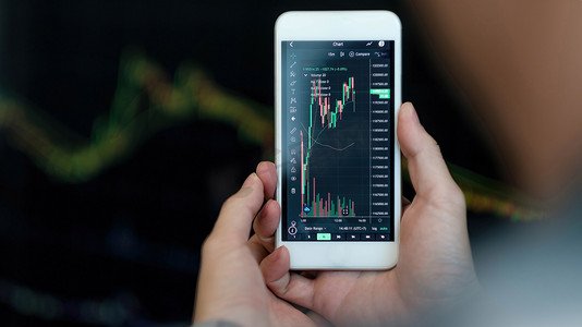 应用程序摄影照片_商人交易员投资者分析师使用手机应用程序分析进行加密货币金融市场分析，在智能手机上交易数据指数图表。
