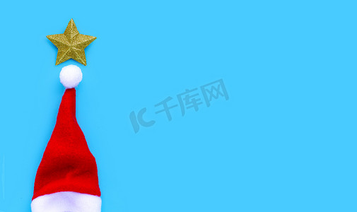 蓝色背景上戴着圣诞老人帽子的金色星星。