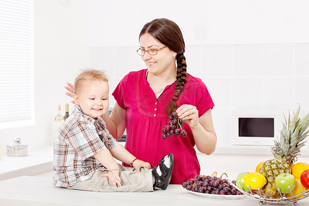 母亲和儿子在厨房里吃水果