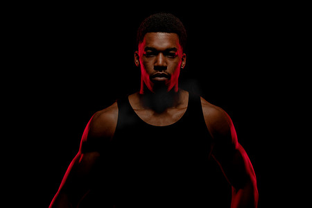 红色的篮球摄影照片_黑色背景下有红色侧光的篮球运动员。