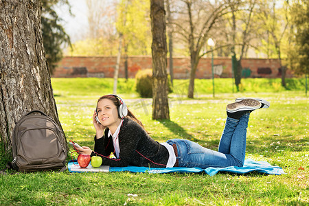 在公园里听音乐的年轻女孩