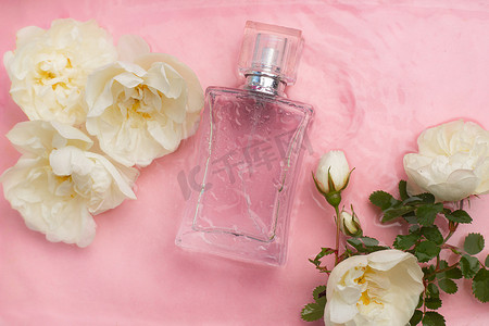 香水瓶和背景上的花朵和水滴。