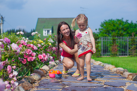 带着可爱女儿的年轻妈妈在花园的夏日里玩得开心