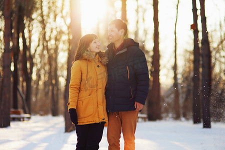 冬日恋人摄影照片_在森林里散步的年轻跨种族微笑夫妇的温暖冬日肖像