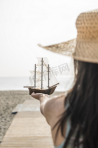 女人在沙滩上拿着船模型