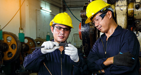 亚洲工程师安全制服使用游标卡尺测量工件。