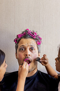 英俊的父亲正在用女儿们的手化妆