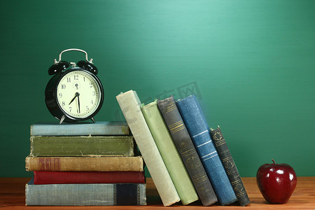 课本、苹果和学校桌上的时钟