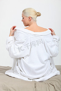 脱下摄影照片_一位女模特在床上脱下浴袍。