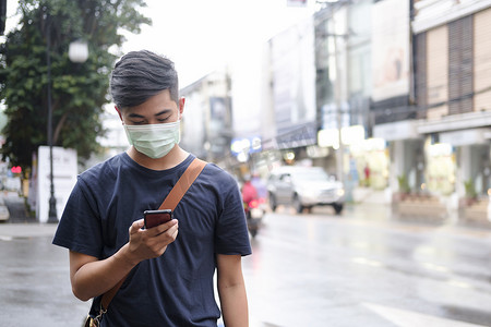 戴防护面罩的年轻人在城市使用手机