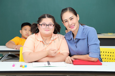 亚洲残疾儿童 或者，一名自闭症儿童在课桌前与老师一起学习阅读、写作和训练他们的手和手指肌肉。