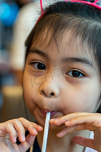 亚洲可爱儿童或小女孩用管子或吸管喝瓶装水或豆奶饮料，吃零食或甜点