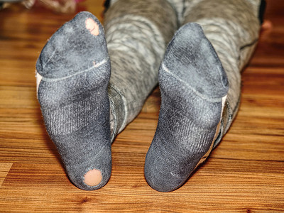 脚汗摄影照片_孩子穿着脚后跟有洞的汗袜子