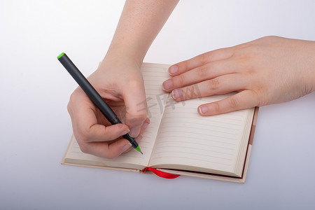 女孩拿着笔在纸上写字的手。