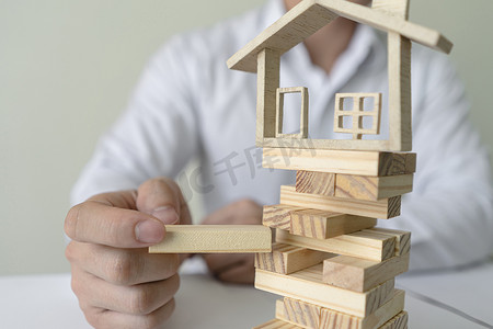 银行工作摄影照片_银行工作人员用模型房子插入木块。