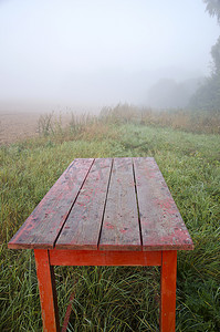 农场花园中的旧红桌和雾中的风景