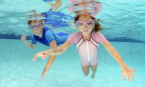 孩子游泳摄影照片_两个孩子在水池里游泳