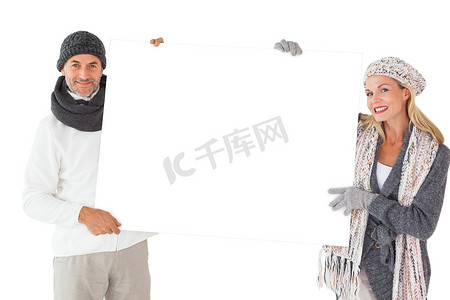 微笑的夫妇在冬季时尚拿着海报