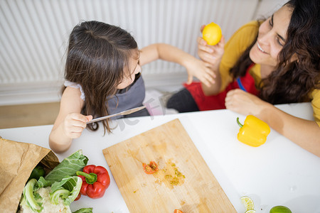 小女孩和她妈妈在砧板上切蔬菜