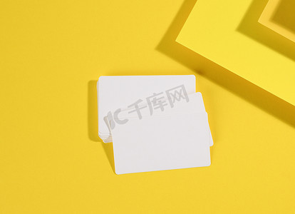 名片设计黄色摄影照片_创意黄色背景上的空白白色矩形名片，来自带阴影的纸片