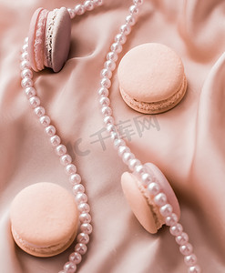 广告马摄影照片_丝绸背景上的甜马卡龙和珍珠首饰、巴黎别致的珠宝、法式甜点食品和豪华糖果品牌的蛋糕马卡龙、节日礼物
