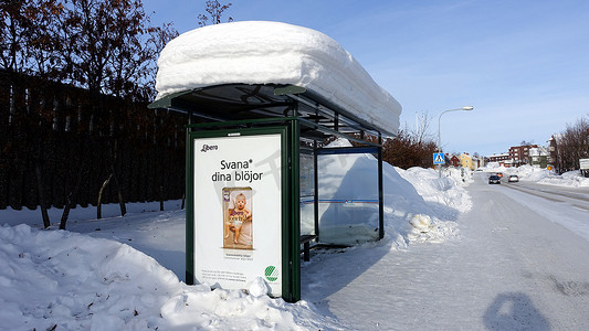 基律纳市中心一条白雪皑皑的街道上，一个满是雪的巴士站