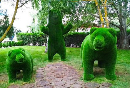 树木背景下人造草的三只熊雕塑。