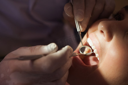牙医在强光下检查牙医椅上病人的牙齿