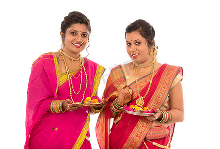 印度传统女孩手持 diya 和花 thali 的肖像，庆祝 Diwali 或 deepavali 的姐妹们在节日期间手持油灯，背景为白色