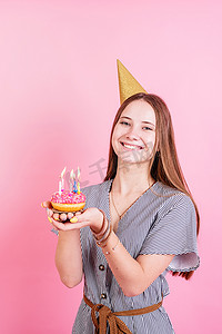 生日许愿摄影照片_金生日的少女拿着带蜡烛的甜甜圈许愿