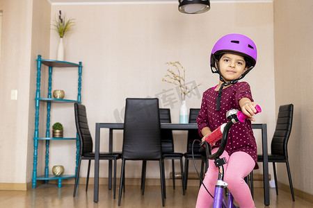彩色图像摄影照片_小女孩在她的客厅里骑自行车