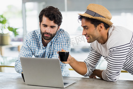 两个朋友在喝咖啡时使用笔记本电脑