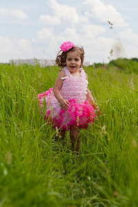 话剧摄影照片_一件桃红色礼服的小女孩跑在草