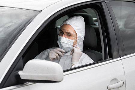身穿防护服、医用口罩和橡胶手套以防细菌和病毒的男子正计划开车。