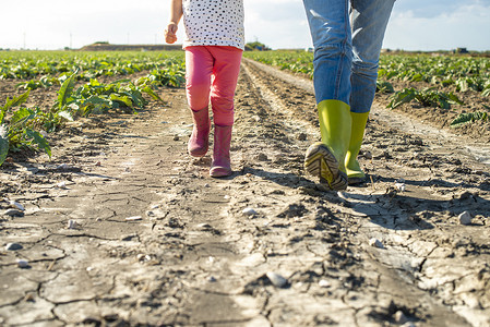 女农夫和小女孩在农田上行走。