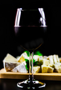木板上的红酒和一组不同的奶酪，美味的小吃