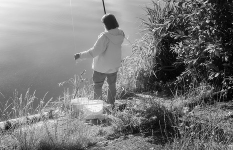 在美丽的湖岸边钓鱼的女人。