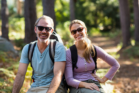 跨年徒步摄影照片_坐在森林岩石上的徒步旅行者夫妇的肖像
