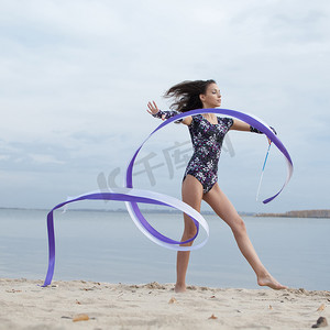 年轻的体操运动员女孩用丝带跳舞