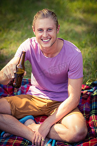 夏季音乐节摄影照片_在营地拿着啤酒瓶的男人的画像