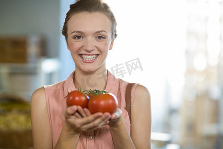 水果商店摄影照片_在杂货店拿着西红柿的女人