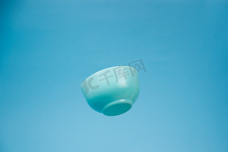 陶瓷器皿摄影照片_一个蓝色陶瓷哑光深碗早餐在蓝色 bac 上飞行