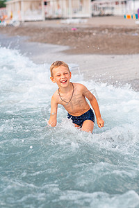 快乐的小男孩在海边的海浪中玩得开心