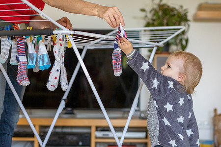 洗衣服男孩摄影照片_可爱的小男孩帮奶奶挂袜子。