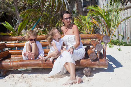 坐在沙滩椅上的年轻母亲和她可爱的女儿们