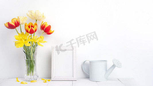 美丽的郁金香花在一个花瓶里，白墙上有相框装饰。
